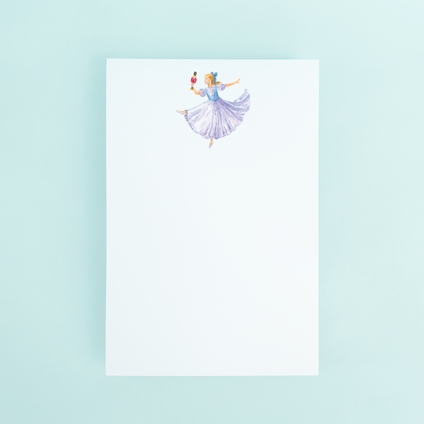 Clara from the nutcracker ballet holding a nutcracker watercolor design on a notepad.