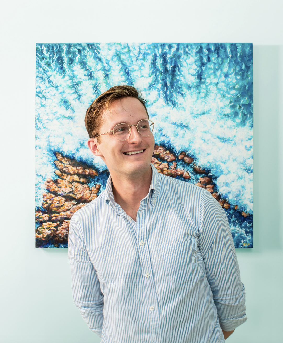 Photo shot of Artist Ben Taylor Paladino with ocean painting behind him