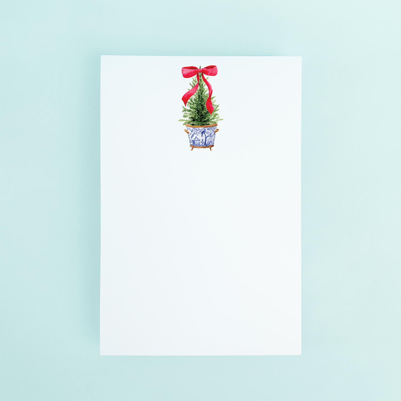 A notepad with a satin bow and ginger jar design on the cover, featuring a Christmas tree motif.