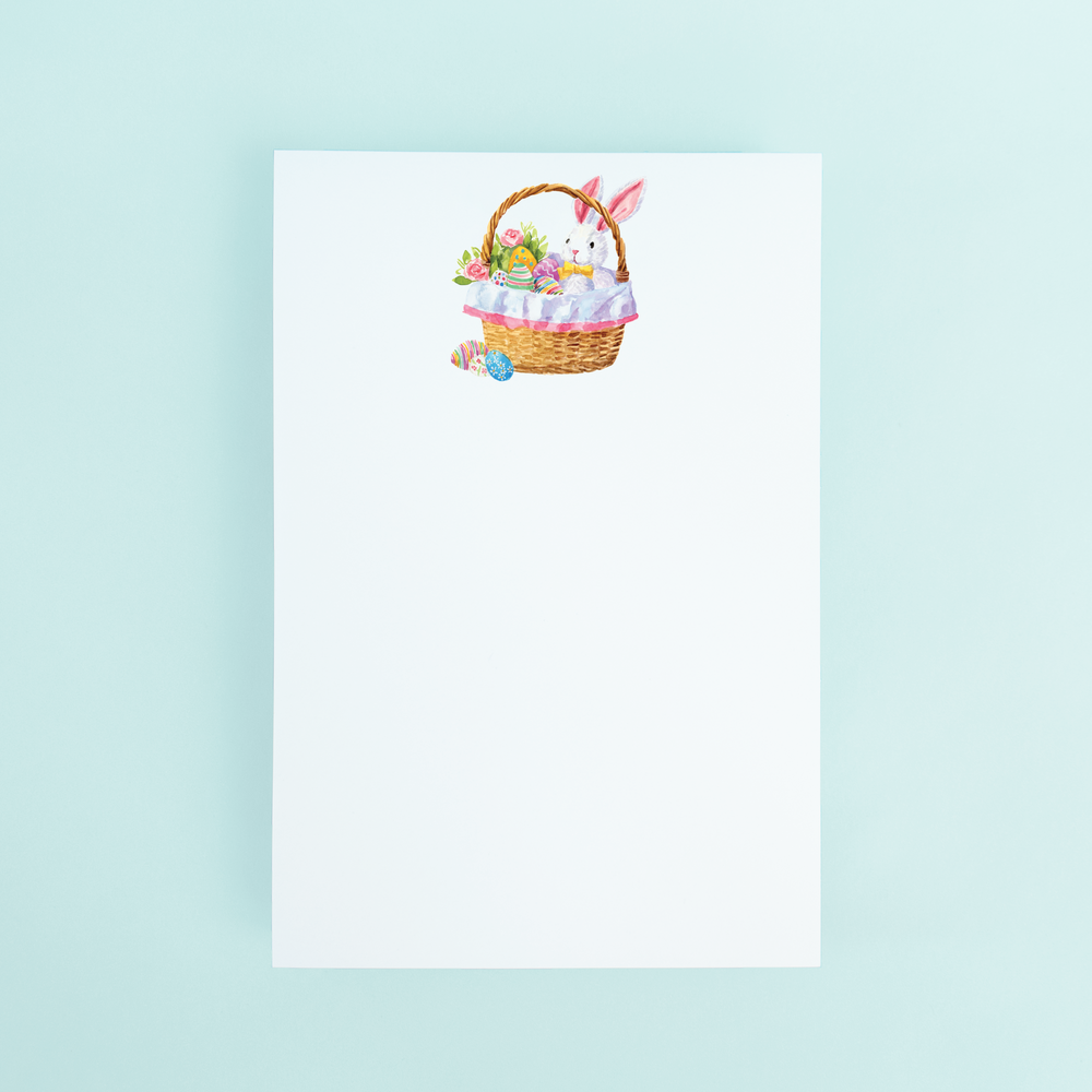 Easterbasket with stuffed bunny and easter eggs in it on a notepad