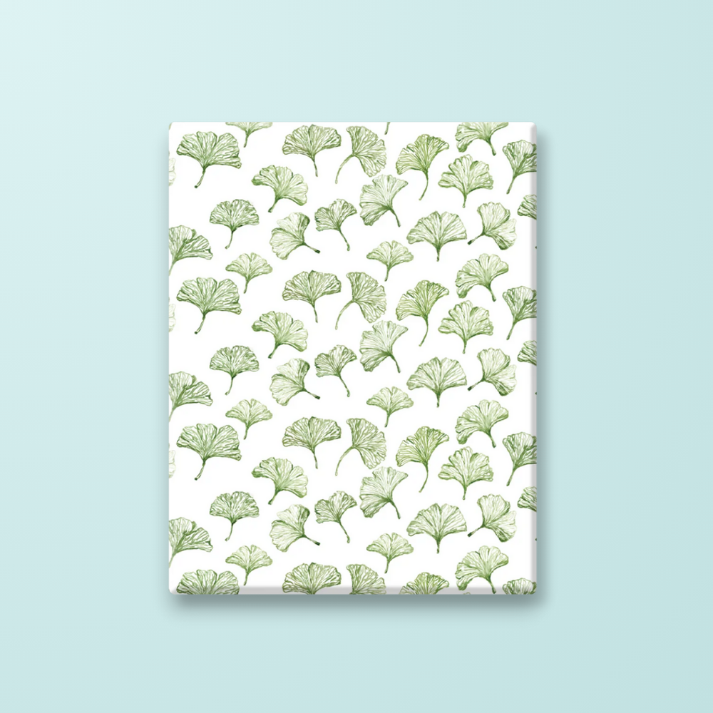 wrapping paper with a white background and watercolor green gingko leaves on it.