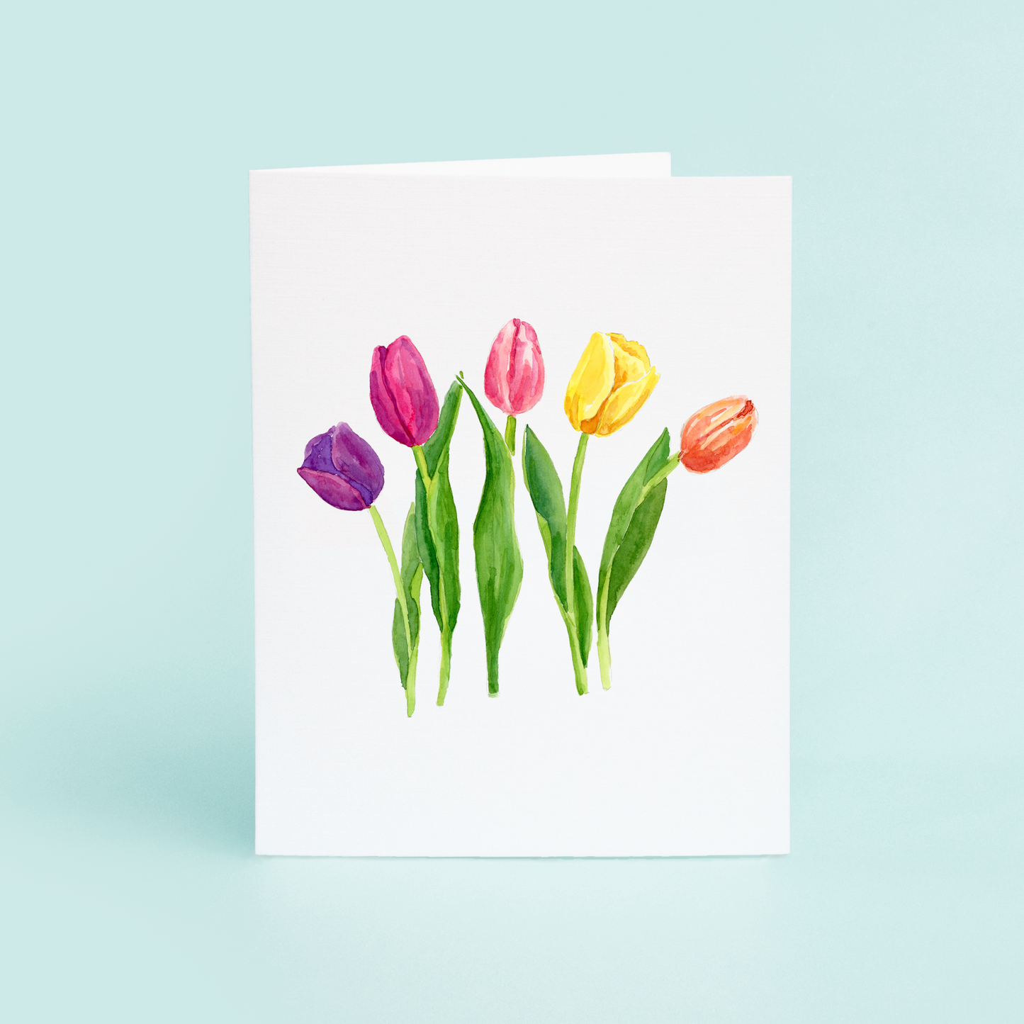 A greeting card featuring a watercolor illustration of five colorful tulips on the front, with a white background.